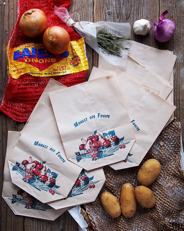 potatoes and onions are sitting on the table next to some paper bags with food in them