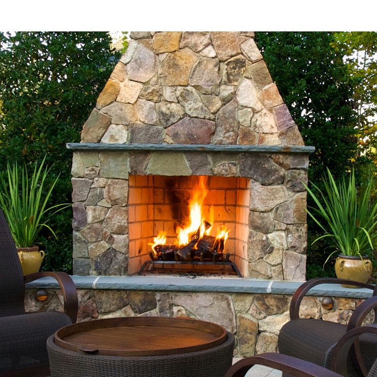 an outdoor fireplace with chairs around it