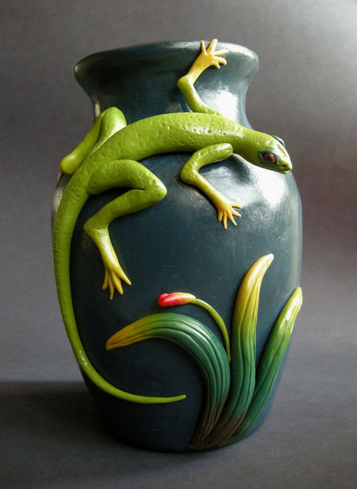 a green vase with two lizards on it's side and flowers in the bottom