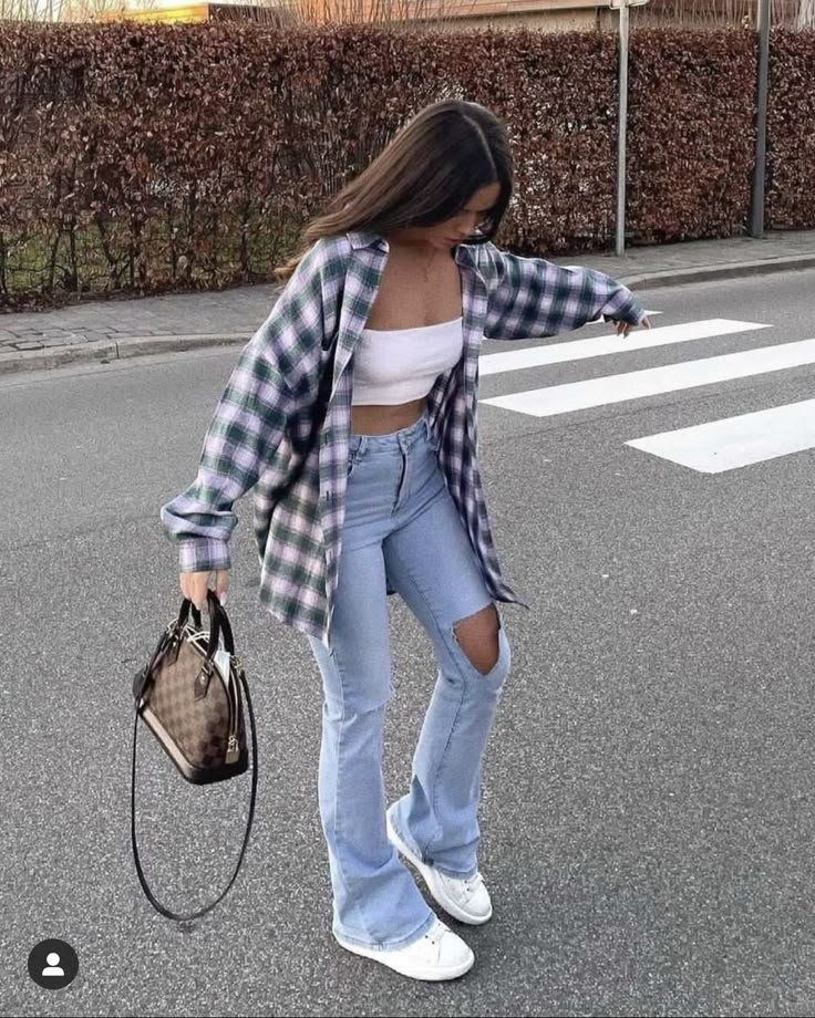 a woman in ripped jeans is crossing the street