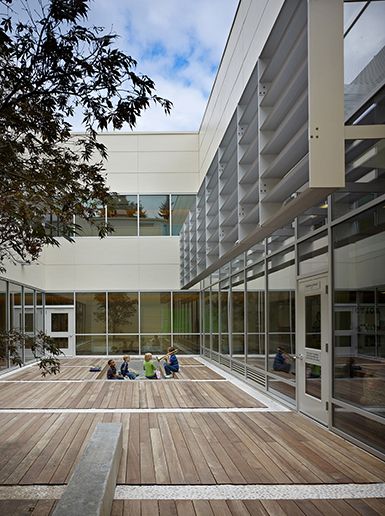 people sitting on the ground in front of a building with large windows and wooden floors