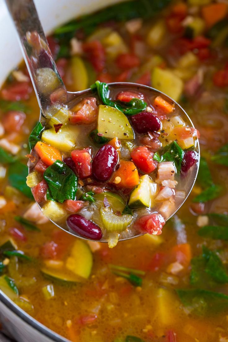 a spoon full of soup with vegetables and beans