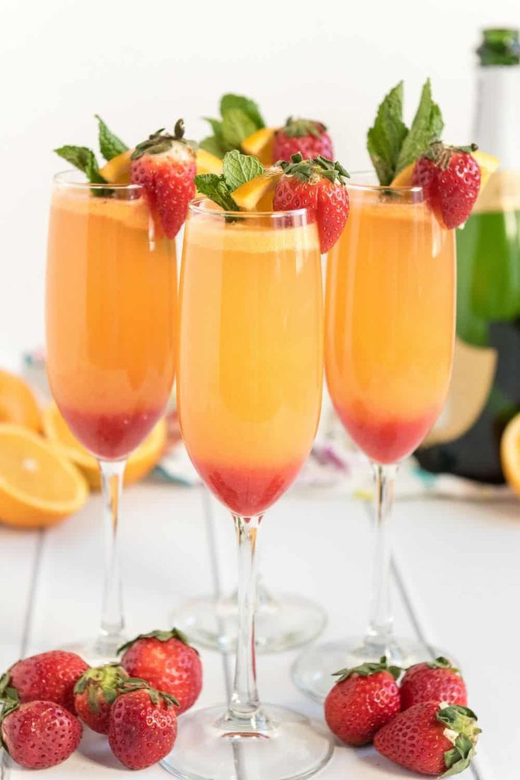 two glasses filled with orange juice and garnished with strawberries