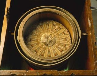 an empty wooden box with a decorative object in it's center, inside which is also a piece of wood