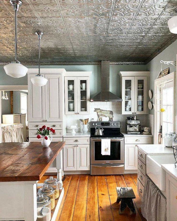 a kitchen with white cabinets and wood floors is pictured in this image, there are lights on the ceiling above the stove