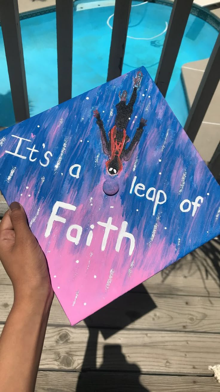 a hand holding up a graduation cap that says it's a leap of faith