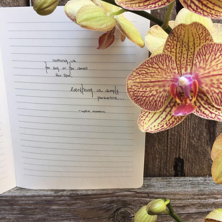 an open notepad with writing on it next to flowers