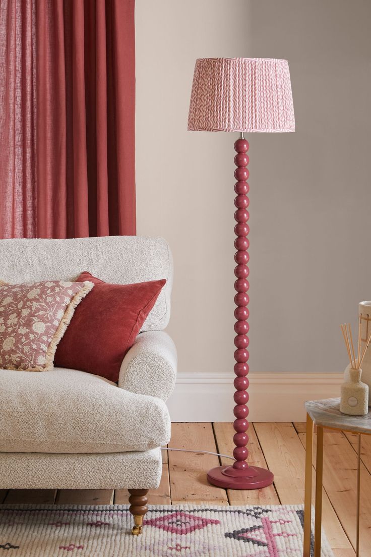 a living room with a couch, lamp and rug on the floor in front of red curtains