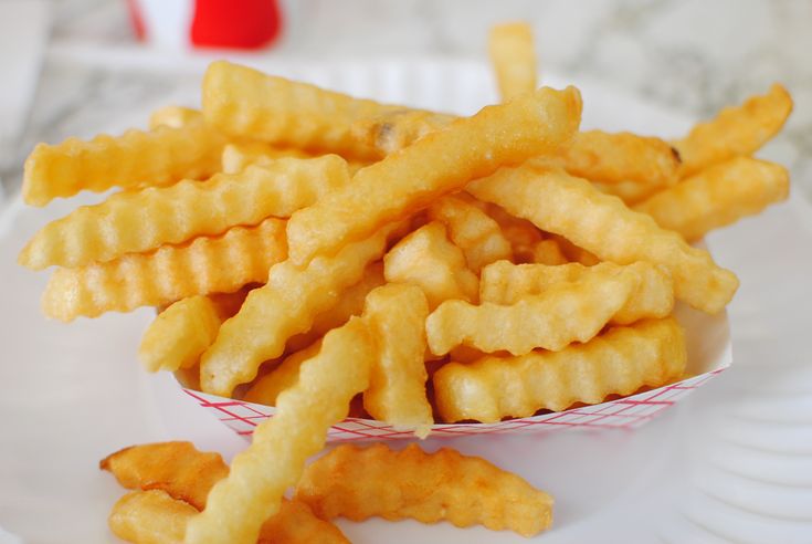 a white plate topped with french fries on top of a table