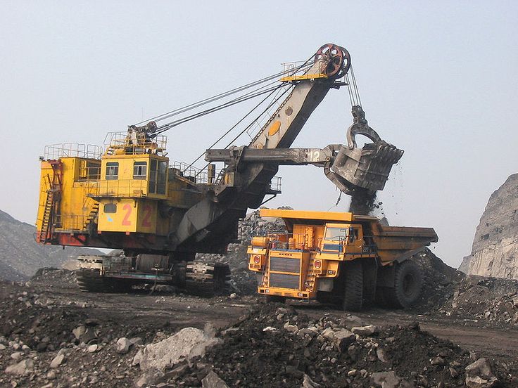 there is a large yellow crane in the middle of some rocks and dirt on this mountain