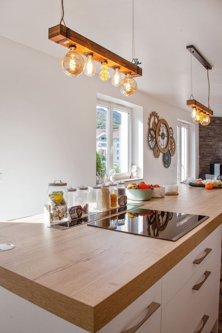 a kitchen with an island and lights hanging from it's ceiling over the counter