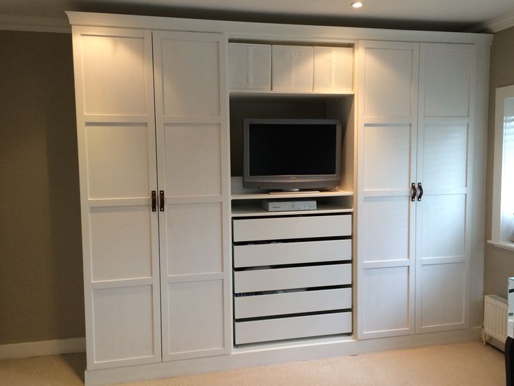 a white entertainment center with drawers and a flat screen tv mounted on it's wall