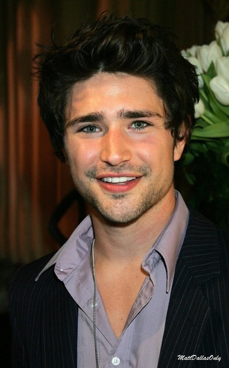 a close up of a person wearing a suit and tie with flowers in the background