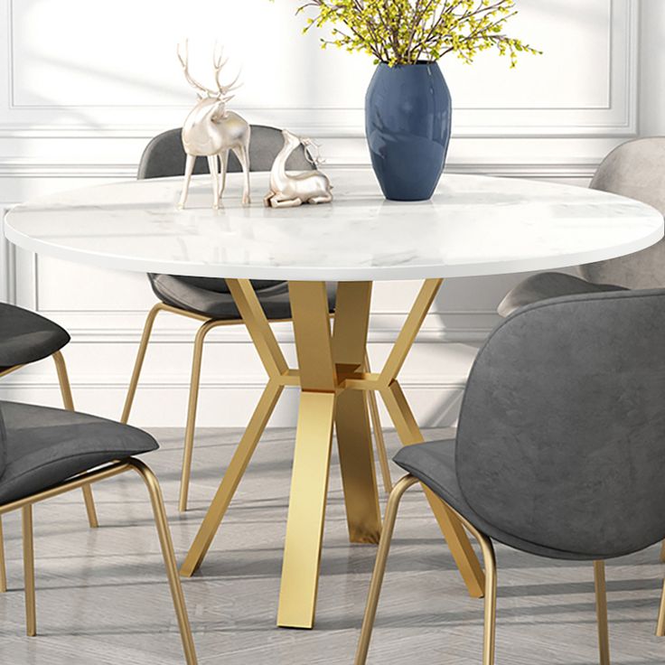 a white table with four chairs around it and a vase on the table next to it