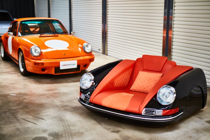 an orange and black car sitting next to each other in front of a garage door