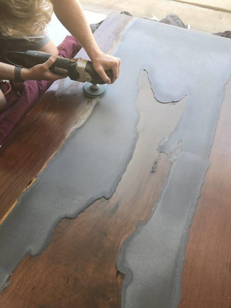 a person using a drill to paint the top of a piece of wooden flooring