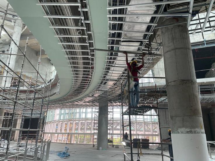 a man on a scaffolding system working on the ceiling in a large building