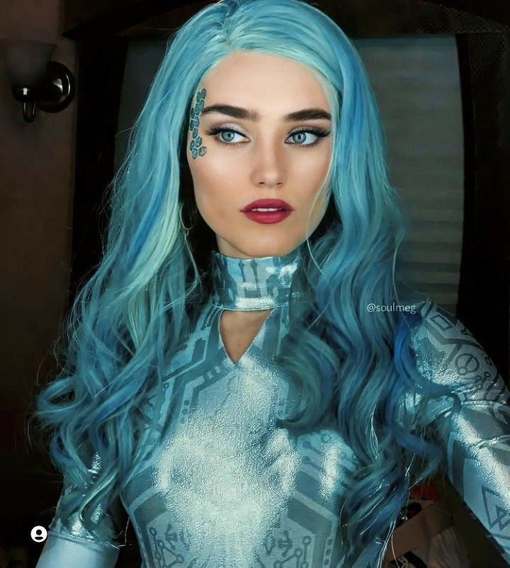 a woman with blue hair and silver outfit