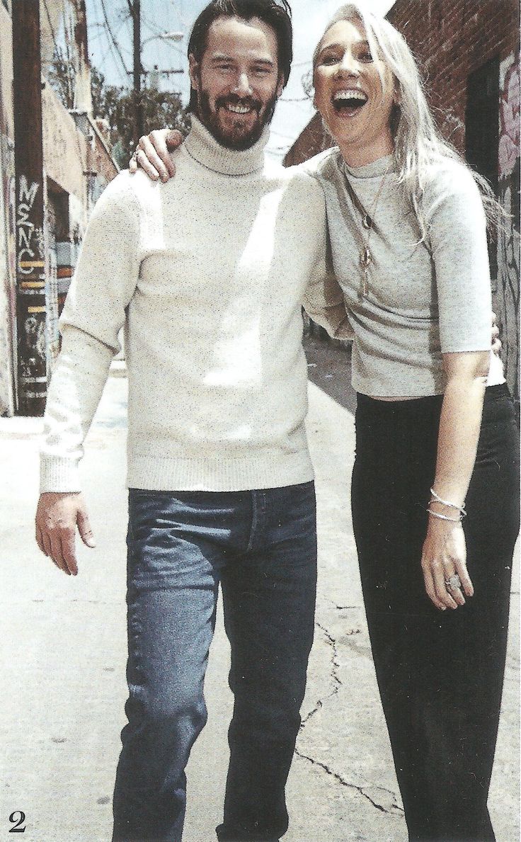 a man and woman are walking down the street smiling for the camera while they both have their arms around each other