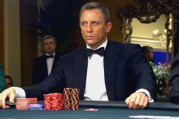 a man in a tuxedo sitting at a table with poker chips