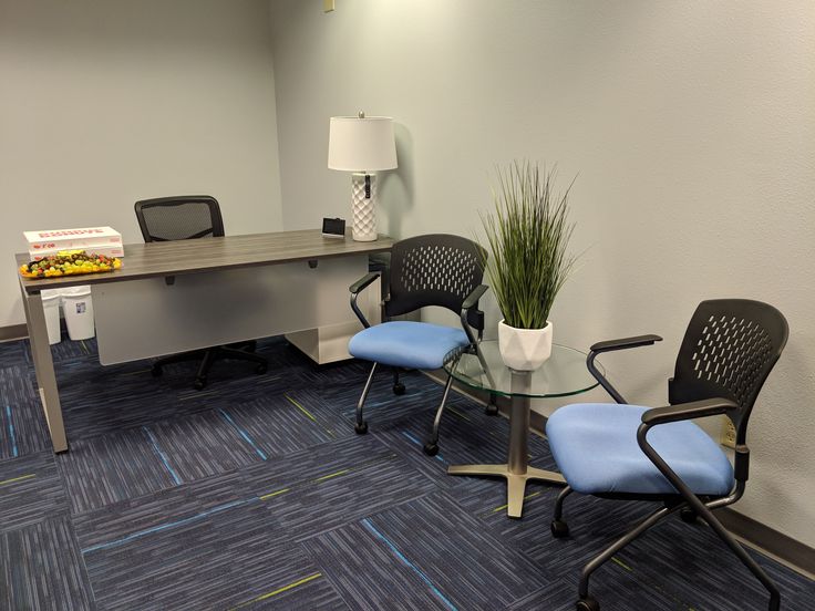 an office cubicle with two chairs and a glass table in front of the desk