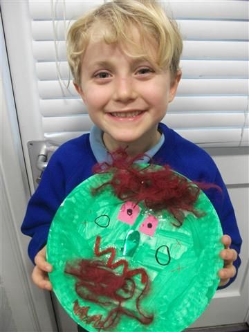 a young boy holding up a paper plate with an image of a monster on it