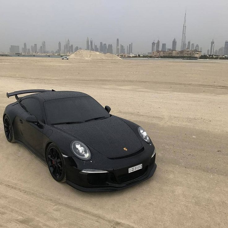 a black sports car is parked in the sand