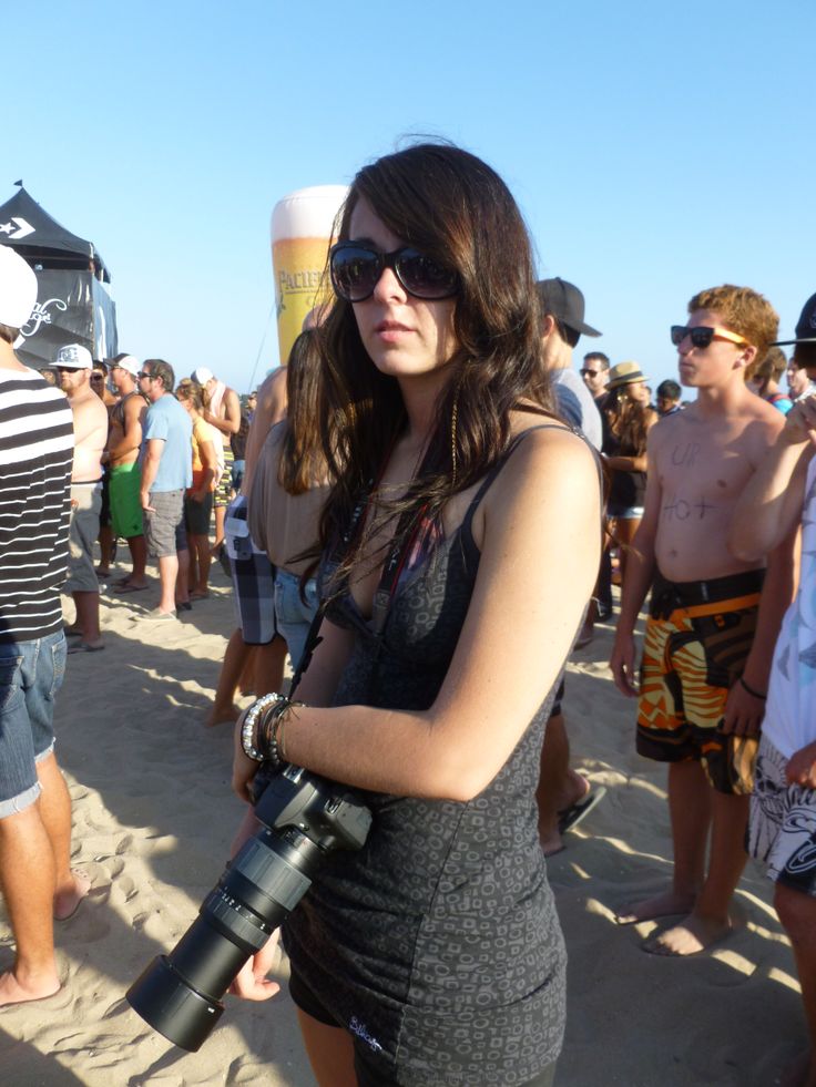 a woman holding a camera on the beach