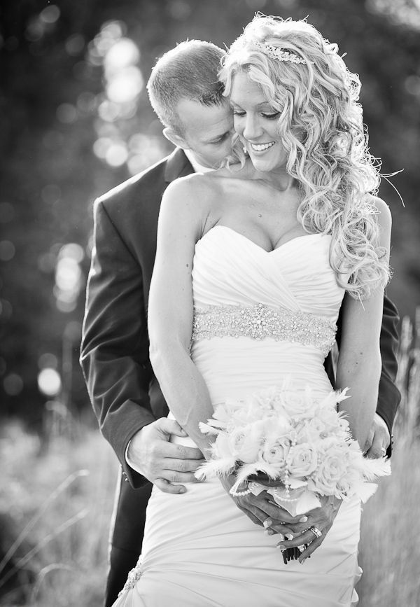 a bride and groom standing together in the grass