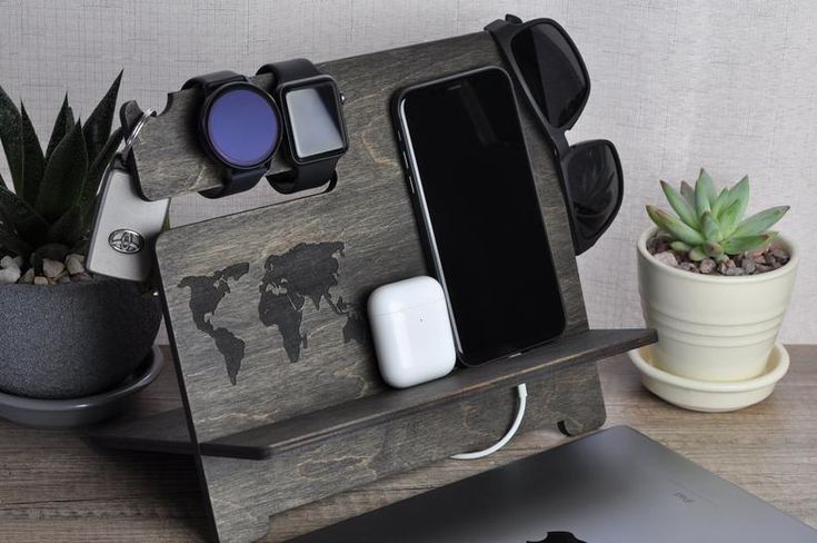 an apple laptop computer sitting on top of a wooden desk next to a plant and cell phone