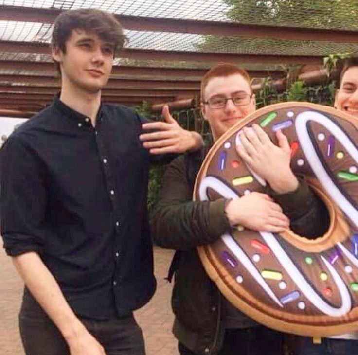 three people are posing with a giant doughnut