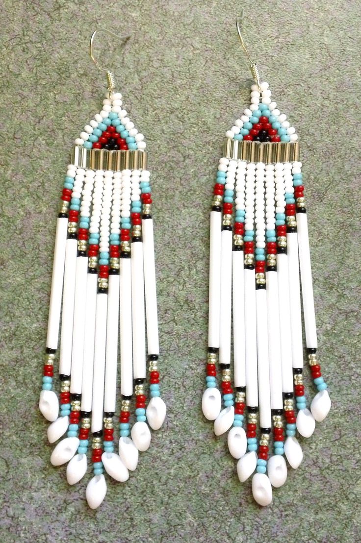 two white and red beaded earrings with beads on the bottom, one is hanging from a