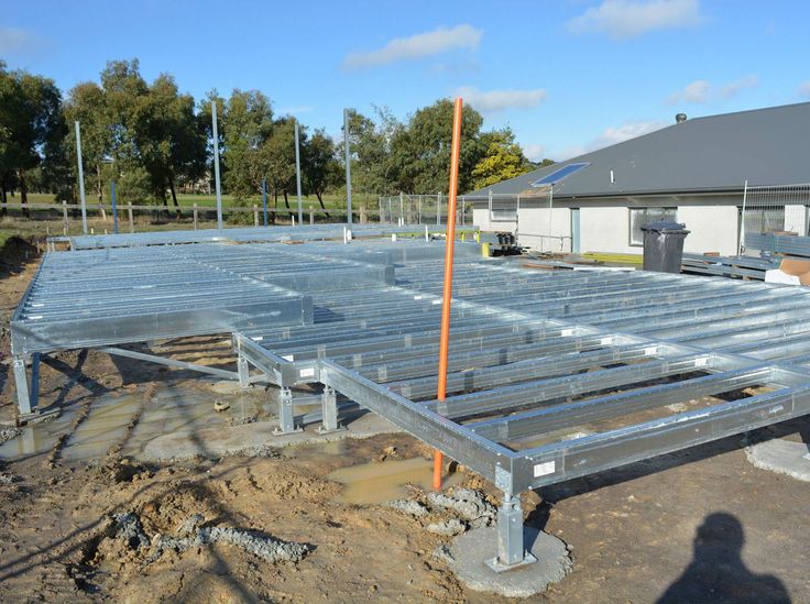 an unfinished metal structure in the middle of a construction site with workers standing around it