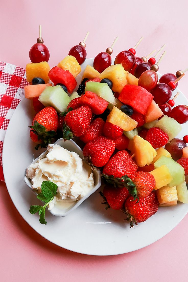 fruit skewers are arranged on a white plate