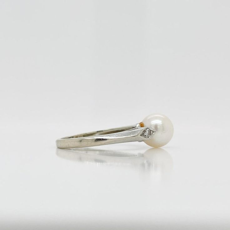 A fine Retro signed pearl cocktail ring.  In 14k white gold.  Set with 7mm round white pearl and flanked by two small accent diamonds on the shoulder of the setting.  Marked to the shank for Rothman & Schneider of New York City.  Simply a wonderful Mid-Century ring!  Date: Mid-20th Century  Overall Condition: It is in overall good, as-pictured, used estate condition with some fine & light surface scratches and other signs of expected light wear consistent with age.  Fineness: Marked 14k for gold Classic White Pearl Ring With Diamond Accents, Classic Pearl Ring With Diamond Accents For Anniversary, Timeless White Gold Pearl Ring With Diamond Accents, Timeless White Round Cut Pearl Ring, White Timeless Round Cut Pearl Ring, Classic White Gold Pearl Ring With Diamond Accents, White Pearl Ring With Diamond Accents, Classic Pearl Ring With Prong Setting In Diamond White, Classic Diamond White Pearl Ring With Prong Setting