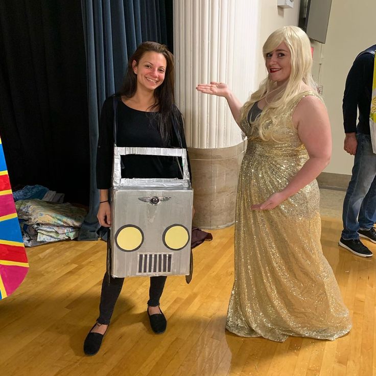 two women dressed in costumes standing next to each other on a hard wood floored area