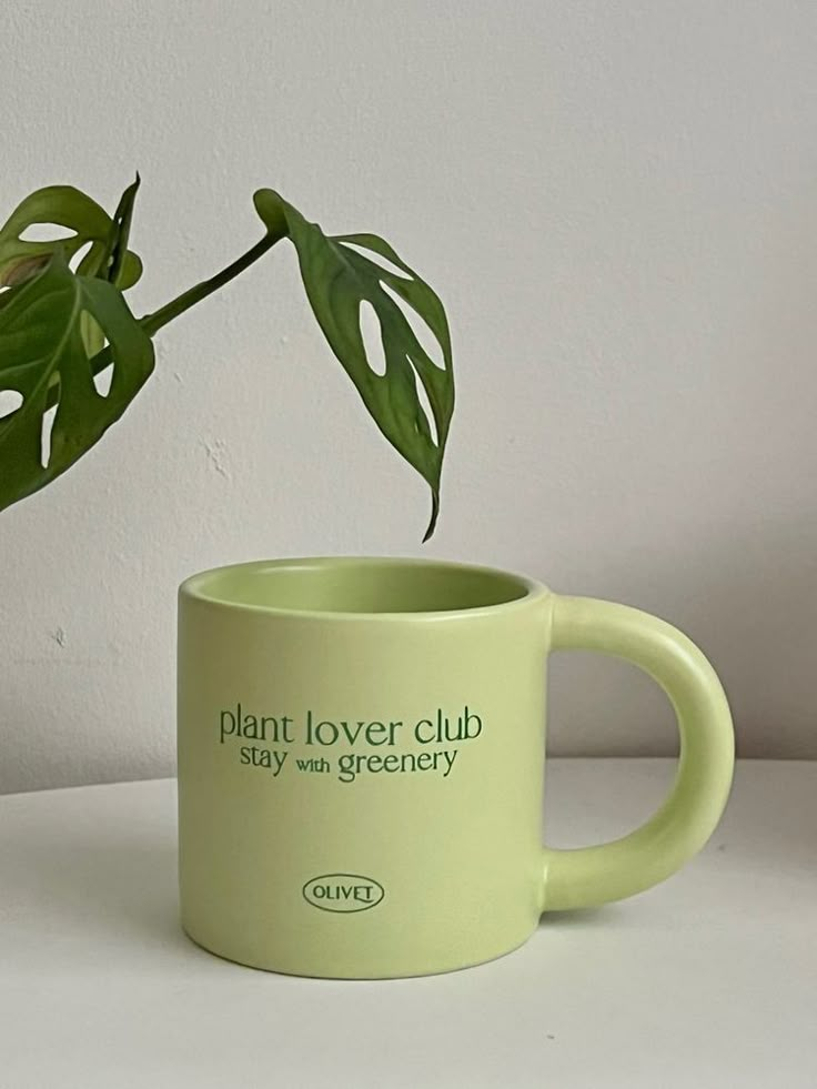 a green coffee mug with a plant in it