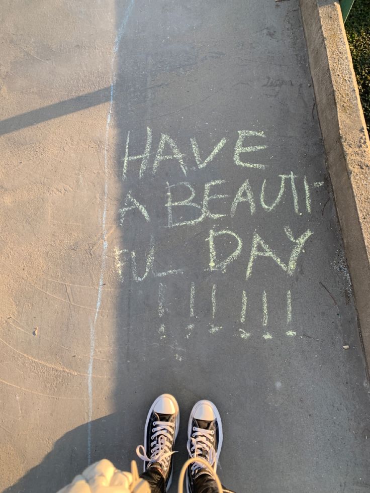 someone is standing on the sidewalk with their feet up and writing have a beautiful day