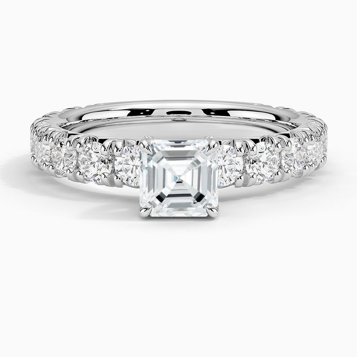 Asscher Cut Luxe Ellora Diamond Engagement Ring - 18K White Gold. This classic engagement ring features sparkling diamond accents that extend three-fourths of the way around the ring. A diamond adorned gallery and graceful claw prongs embrace the center gem (1 2/5 total carat weight). White Gold Diamond Ring With Asscher Brilliant Cut, Promise Ring With Asscher Cut Diamond Accents, White Gold Asscher Cut Diamond Ring With Vvs Clarity, Promise Jewelry With Asscher Cut Diamond Accents, Promise Jewelry With Diamond Accents And Asscher Cut, Asscher Cut Jewelry With Diamond Accents For Promise, Asscher Cut Diamond Promise Ring In Fine Jewelry Style, Timeless Platinum Asscher Cut Diamond Ring, Dazzling Asscher Cut Diamond White Diamond Ring