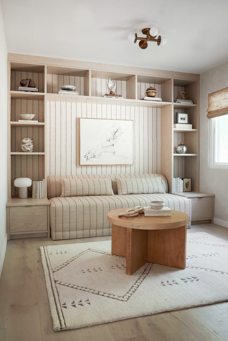 a living room with a couch, coffee table and bookshelf on the wall