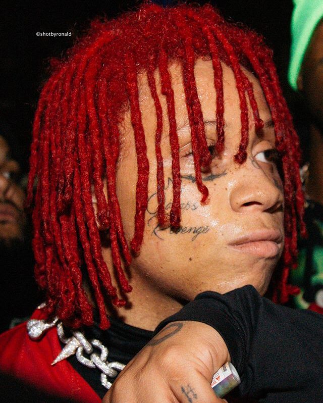 a young man with red dreadlocks on his head and hands in front of him