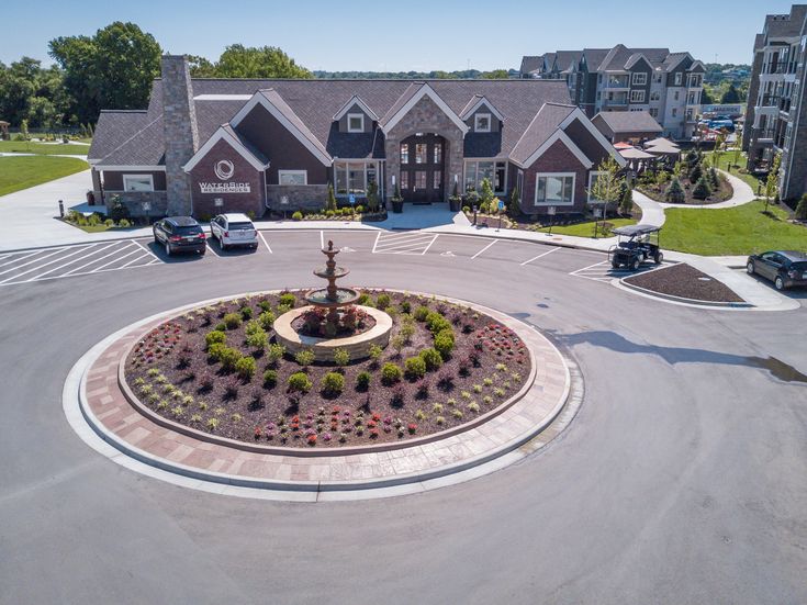 an aerial view of a parking lot with a fountain in the center surrounded by flowers