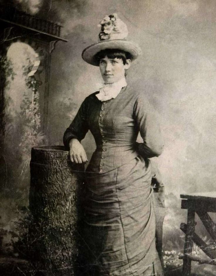 an old black and white photo of a woman wearing a hat