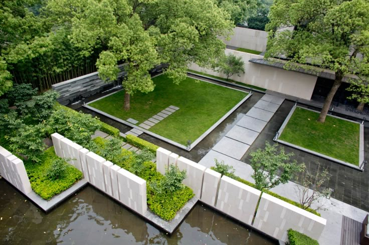 an aerial view of a garden with trees and grass in the center, surrounded by water