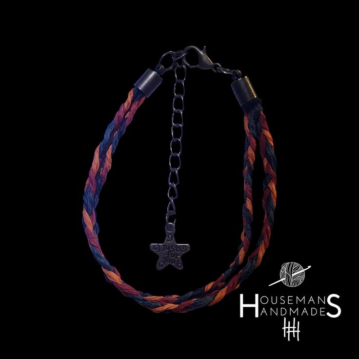 a multicolored rope bracelet with a cross charm on the end and a black background