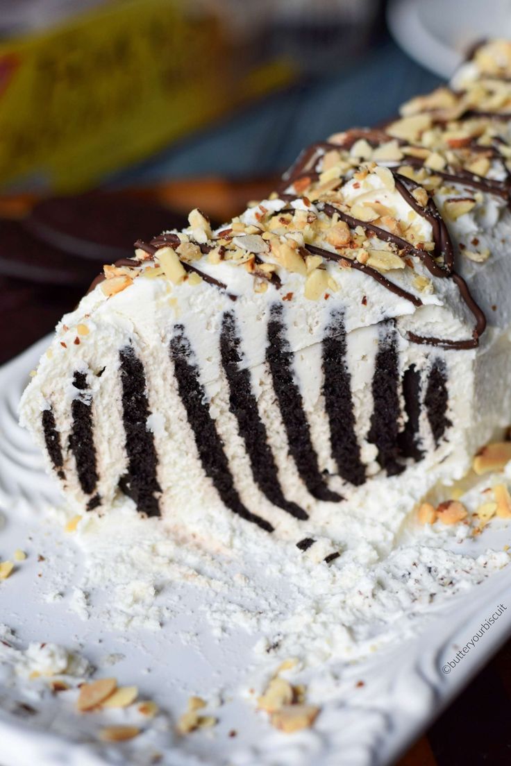 a slice of ice cream cake on a white plate with nuts and chocolate toppings