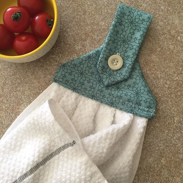 a bowl of tomatoes and a pair of white towels on the floor next to a dish towel