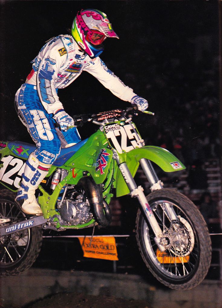 a man riding on the back of a dirt bike in front of a large crowd