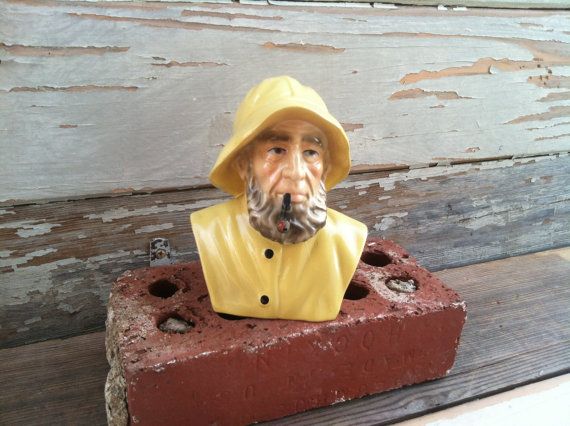 a statue of a man wearing a yellow hat and coat on top of a brick