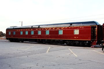 a red and black train car parked in a parking lot next to a motor scooter